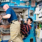２０１５年８月、専用装置を使って目を検査する油井亀美也さん（右）（国際宇宙ステーション、ＪＡＸＡ／ＮＡＳＡ提供）