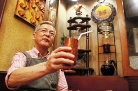 専用器具（右）を使って抽出したコーヒーを手にする立花吉博さん＝西宮市津門川町