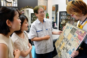 「理容なかもと」で２代目店主の中本博行さん（右から２番目）から話を聞くきたっ子むすめの２人＝北区鈴蘭台北町１