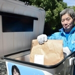 新聞配達用のボックスに荷物を詰める配達員＝神戸市北区ひよどり台５
