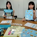 自作した缶バッジとクリアファイルを紹介する学生たち＝神戸芸術工科大学