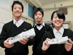 新聞紙で作ったスリッパを持つ窑子高校環境防災科の（左から）武中大空さん、為平さん、山本千智さん＝神戸市垂水区学が丘３