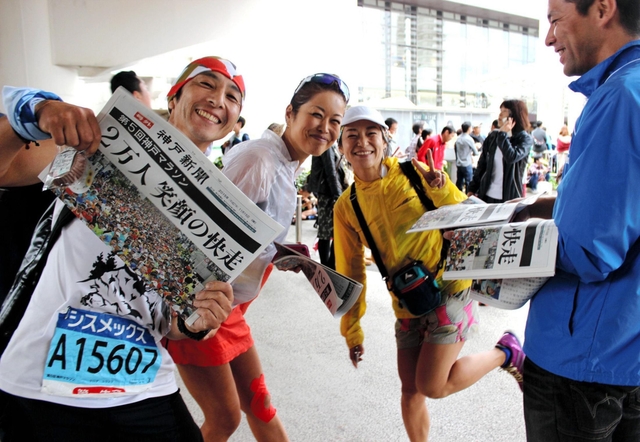 神戸マラソン開催を伝える号外を受け取るランナー＝１５日午後、神戸市中央区港島中町６