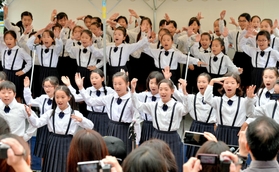 時折雨が降るなか、ステージで歌うなぎさ小学校の児童ら＝１４日午後、ＪＲ三ノ宮駅前（撮影・後藤亮平）