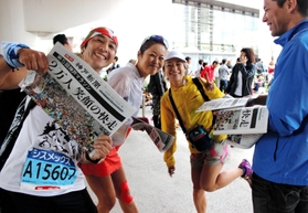神戸マラソン開催を伝える号外を受け取るランナー＝１５日午後、神戸市中央区港島中町６