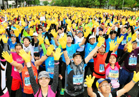スタート前に、復興の象徴ヒマワリに見立てた黄色い手袋を掲げるランナーたち＝神戸市中央区、市役所前