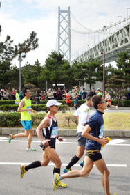明石海峡大橋を臨む折り返し地点を通過するランナーたち＝神戸市垂水区東舞子町