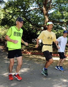 伴走者と共に走る芝山孝雄さん（左）＝明石市、明石公園