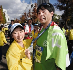 今春から神戸学院大学で学ぶ仙台出身の新妻彩乃さん（左）が、完走した父の英敏さんにメダルを掛けた＝神戸市中央区港島中町６（撮影・中西大二）