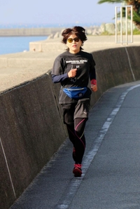 神戸マラソンに向けて、堤防沿いの道を走る山本弥生さん。ウエストポーチとタイツは長女からのプレゼント＝明石市大久保町江井島
