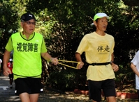 猛暑の８月、練習会で汗を流す芝山孝雄さん（左）＝明石市、明石城公園