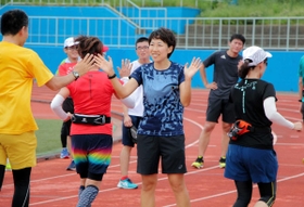 ランナーをハイタッチでねぎらう中村友梨香さん＝王子スタジアム
