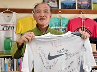 かつての教え子の応援メッセージが入ったＴシャツを手に意気込みを語る山本民夫さん＝神戸市須磨区