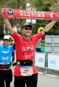 「がんばろう熊本」と書かれたタオルを掲げてゴールする町田幸三郎さん＝いずれも神戸市中央区港島中町６（撮影・斎藤雅志）