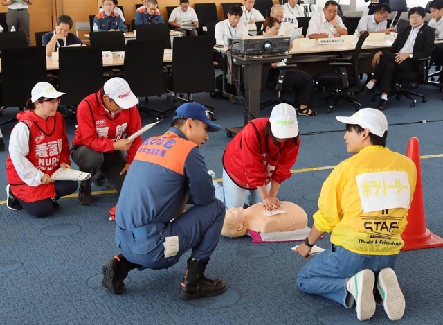 急病人の心肺蘇生や搬送時の手順を確認する訓練参加者ら＝神戸市中央区港島１