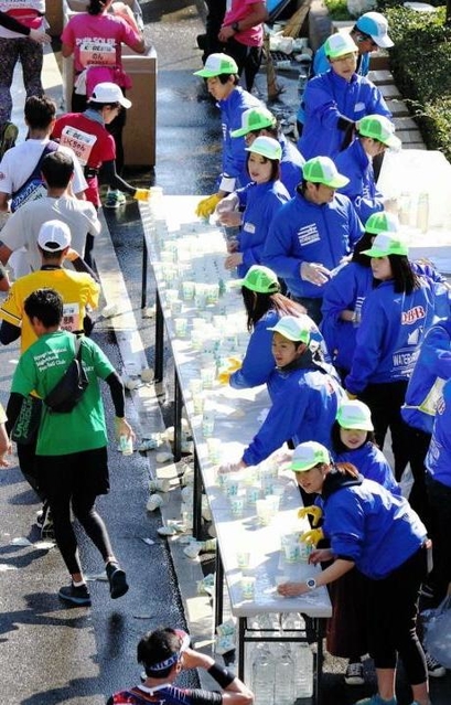 昨年の神戸マラソン。ランナーたちに水を配るボランティアら＝神戸市垂水区