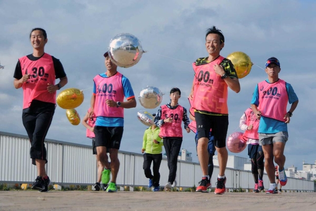 設定時間の入ったビブスと目印の風船をつけて走るペースセッター＝神戸市中央区脇浜海岸通１、ＨＡＴ神戸