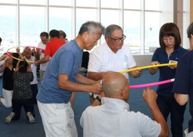 フラフープを使ってチームワークを養うゲームに取り組む参加者ら＝神戸市中央区港島１