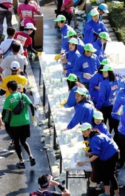 昨年の神戸マラソン。ランナーたちに水を配るボランティアら＝神戸市垂水区