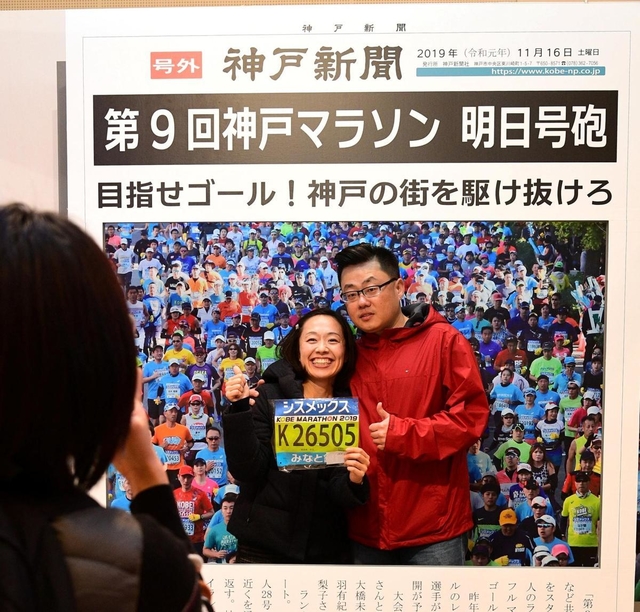 新聞の号外紙面を模した撮影スポットで記念撮影するランナーら＝神戸市中央区港島中町６（撮影・秋山亮太）