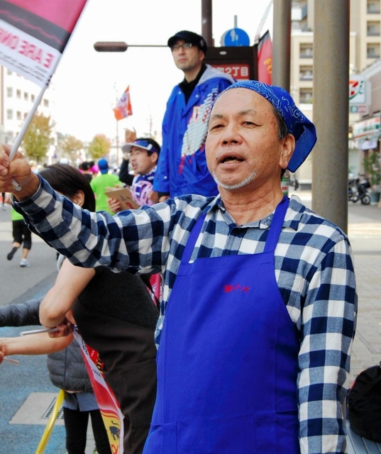 「頑張れ」と旗を振る林誠二さん＝神戸市兵庫区