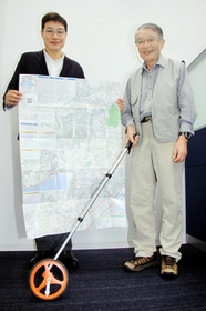 六甲全山縦走路を測ったロードメジャーを手にする守屋益男さん（右）と、完成した地図を広げる次男二郎さん＝神戸新聞社