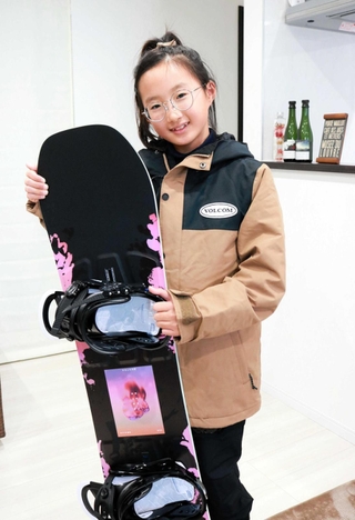 新しく買ってもらったスノーボードを抱えて笑顔の松崎心海さん。ウェアも大人っぽくてお気に入りだ＝高砂市阿弥陀町