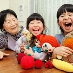 「まきちゃん」こと小林眞紀子さん（左）に作ってもらったぬいぐるみや、人形の洋服を抱きしめて、ご機嫌の三好莉帆さん（右）、華帆さん＝明石市太寺４