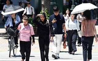 強い日差しを手にかざしたり、日傘を差したりしながら歩く人たち＝５日午後、神戸・三宮（撮影・斎藤雅志）