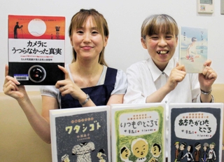 戦争と平和について考える本を手にする伊丹市立図書館の竿本美紀さん（左）と荻野聖子さん＝伊丹市宮ノ前３