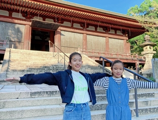 本堂の前で両手を広げる大沼美瑛さん（左）と塩谷茉那さん＝いずれも神戸市西区伊川谷町前開、太山寺