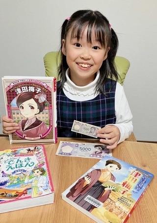 大好きな津田梅子の関連本と、おもちゃの新５千円札を持つ野田いちかさん＝神戸市西区