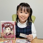 大好きな津田梅子の関連本と、おもちゃの新５千円札を持つ野田いちかさん＝神戸市西区