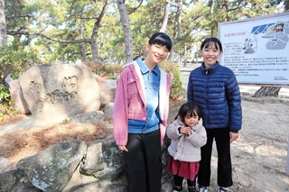 左の石が鵺塚。矢尾成璃子さん（左）と船越えれなさんと妹の芹夏さん。伝説は受け継がれていく＝芦屋市浜芦屋町