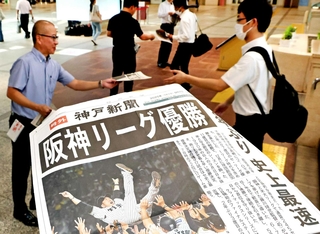 出勤する人らに配布した阪神リーグ優勝を伝える神戸新聞の号外＝８日午前、神戸市中央区、デュオこうべ
