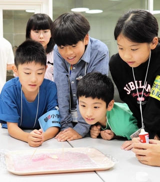 ゼリーを使った火山の実験を体験するこども記者ら＝長野県松本市