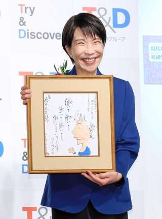 選考委員の漫画家やくみつるさんの直筆イラストを手にする高市首相＝東京都千代田区