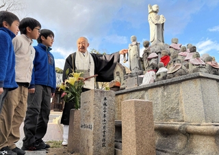 各地から移された「神戸震災地蔵尊」について、朝倉経義住職から話を聞く川さん兄弟＝神戸市須磨区須磨寺町４