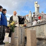 各地から移された「神戸震災地蔵尊」について、朝倉経義住職から話を聞く川さん兄弟＝神戸市須磨区須磨寺町４