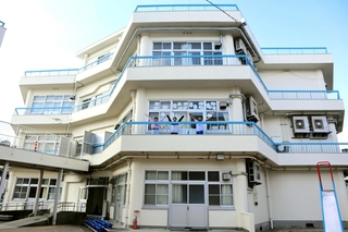 上から見るとカクカクした形の「ハチの巣校舎」。教室の外に出て手をあげた３人＝神戸市垂水区塩屋町３、塩屋小学校