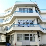 上から見るとカクカクした形の「ハチの巣校舎」。教室の外に出て手をあげた３人＝神戸市垂水区塩屋町３、塩屋小学校