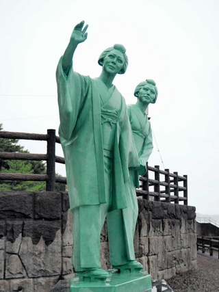 坂本龍馬像に手をふるお龍（左）と妹の君枝の銅像＝高知県芸西村の琴ケ浜