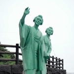 坂本龍馬像に手をふるお龍（左）と妹の君枝の銅像＝高知県芸西村の琴ケ浜