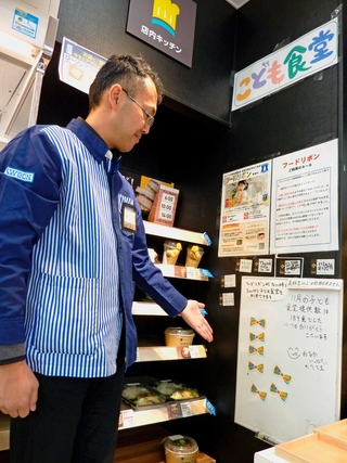 店内のボードにはられたリボンを見せるローソン宝塚市役所前店オーナーの森下忠明さん＝兵庫県宝塚市