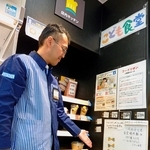 店内のボードにはられたリボンを見せるローソン宝塚市役所前店オーナーの森下忠明さん＝兵庫県宝塚市