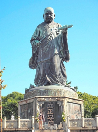 「立正安国論」の巻物を持つ日蓮の大銅像＝福岡市博多区