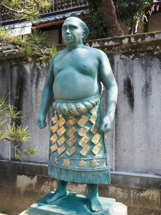 けしょうまわし姿で立つ大鵬幸喜さんの銅像＝三重県鈴鹿市の龍光寺