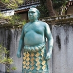けしょうまわし姿で立つ大鵬幸喜さんの銅像＝三重県鈴鹿市の龍光寺