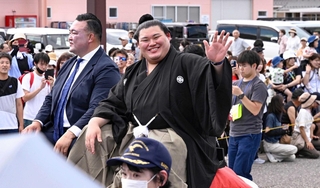 石川県津幡町で行われた横綱昇進を祝うパレードで、集まった人たちの声援にこたえる大の里。左は二所ノ関親方＝６月