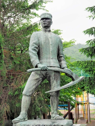 軍服にわらじをはいた姿で、くわを持つ屯田兵の像＝札幌市中央区